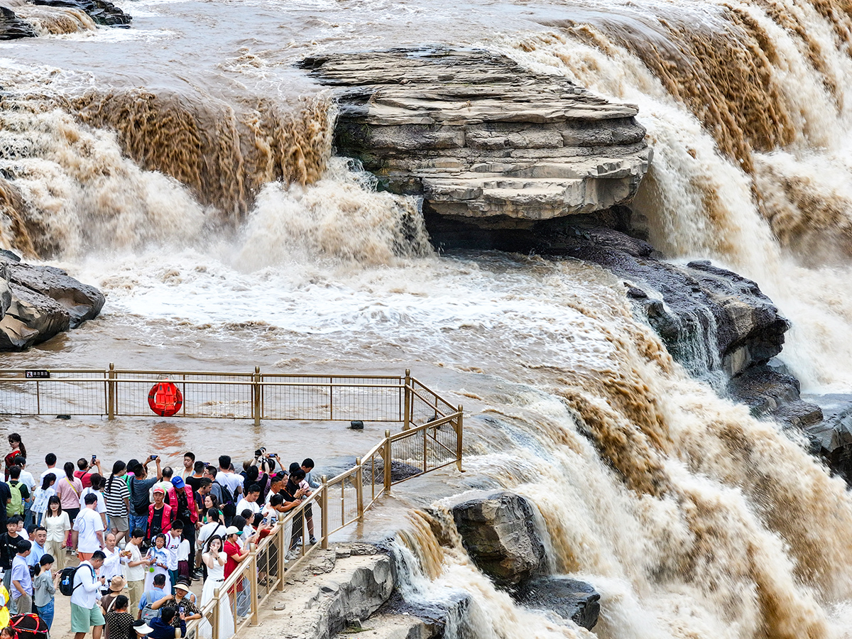 Туристы наблюдают за усилившимся потоком воды в водопаде Хукоу на реке Хуанхэ возле города Линфен, китайская провинция Шаньси, 15 августа 2024 года. Фото: Reuters